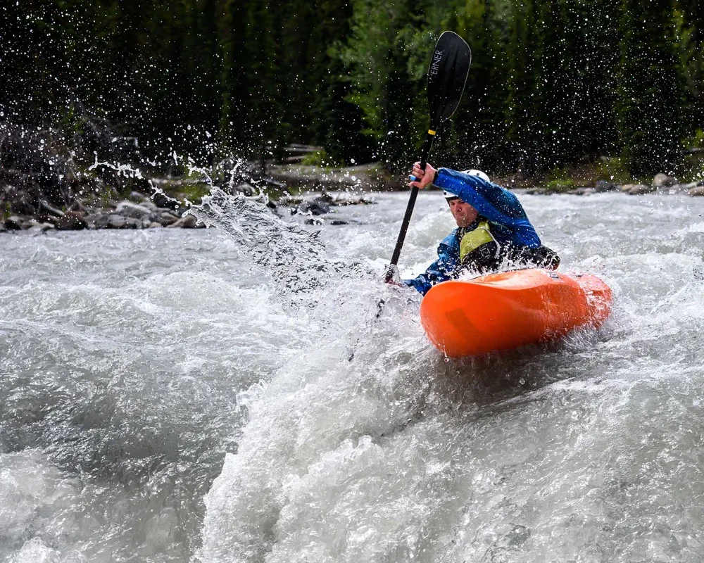 Daring Kayaker navigates tricky falls. Athlete is concentrating and controlling his kayak.