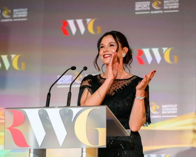 A famous speed skater hosting a Gala standing behind a podium.
