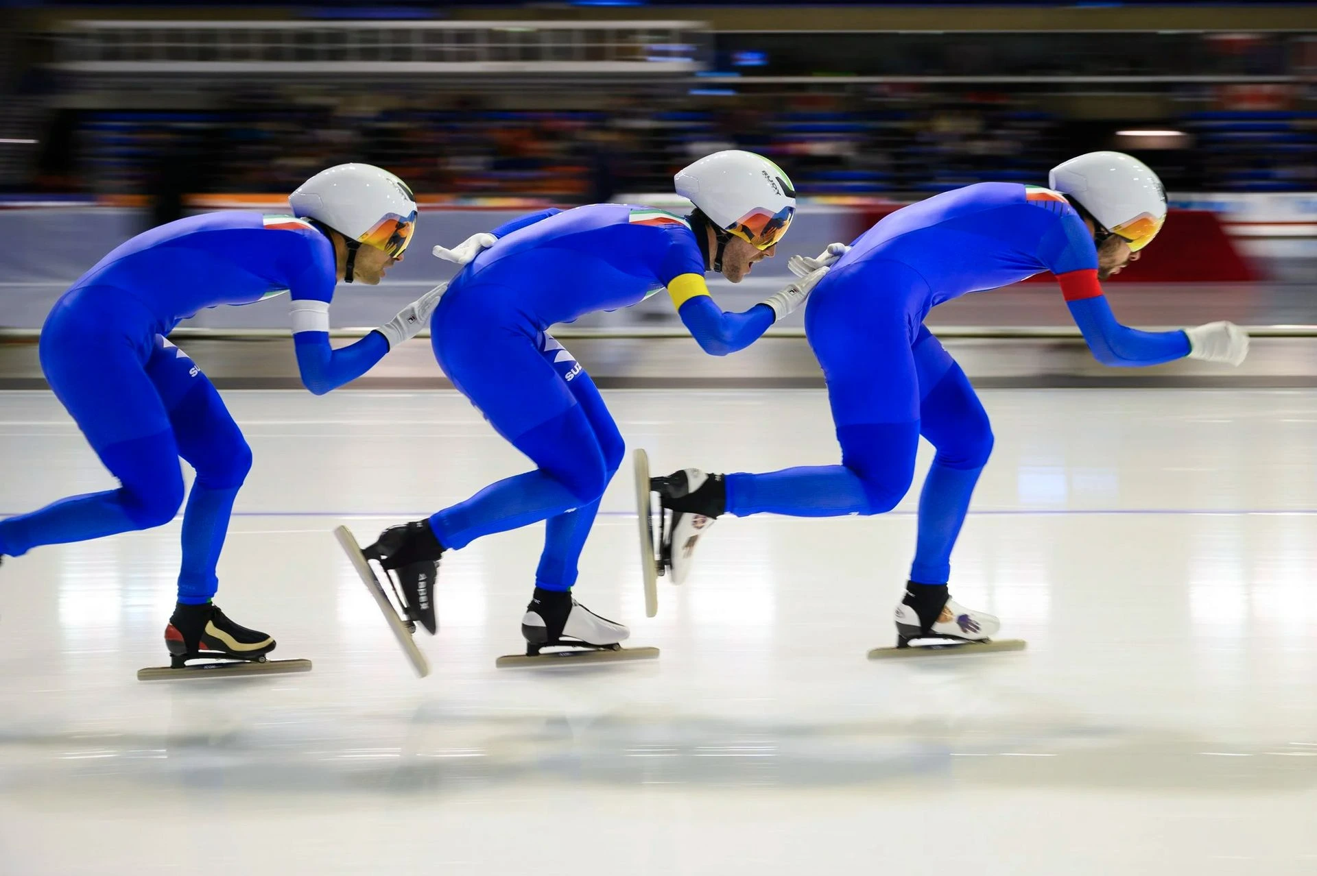 Fast action. Speed skaters race in bright blue suits, and win the gold medal.